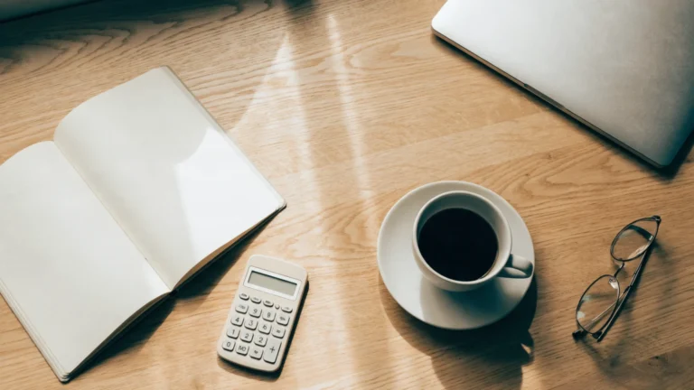 Desk with an open notebook, calculator and coffee used to plan a monthly SEO budget